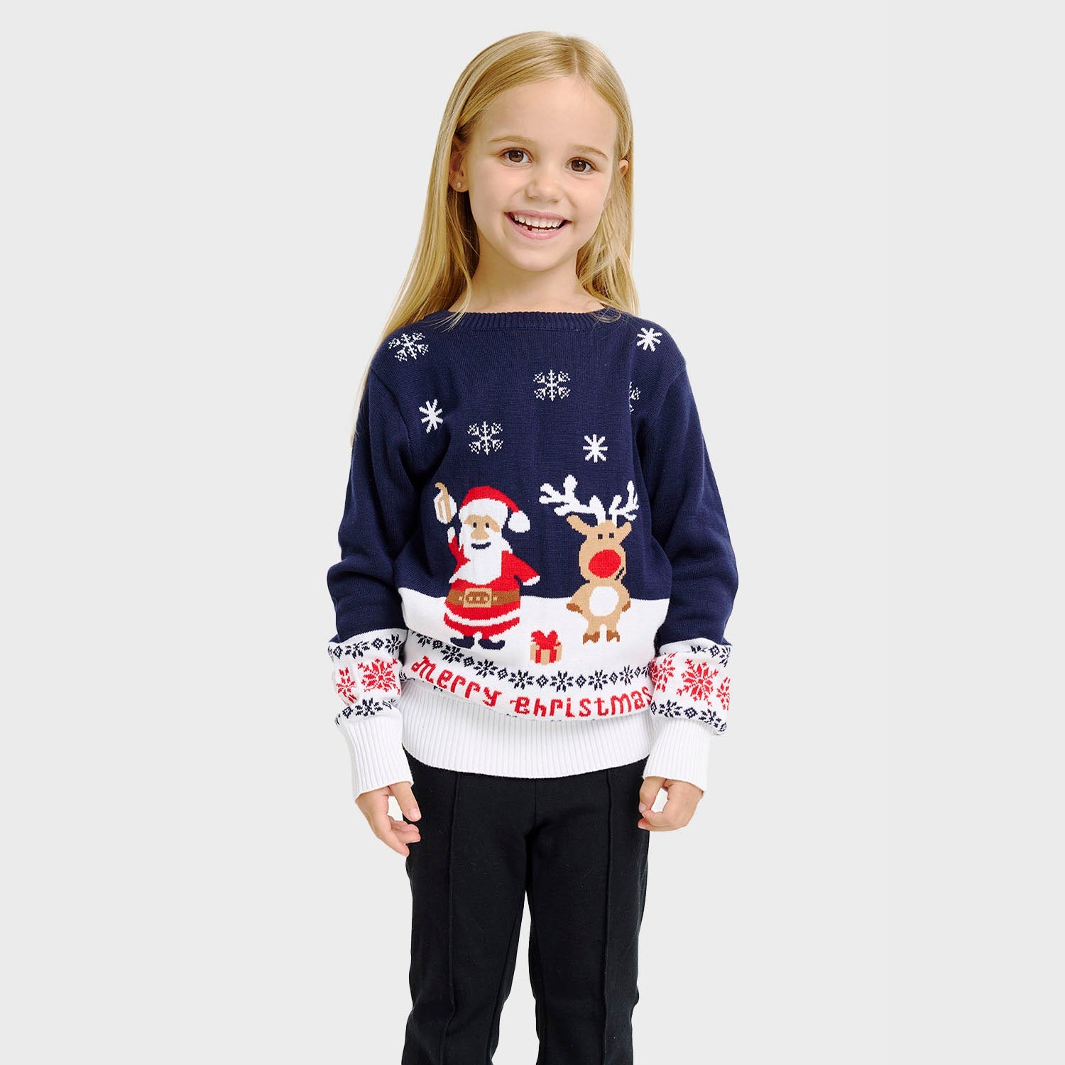 Ein Kind, das einen blau-weißen Weihnachtspulli mit Rudolph und dem Weihnachtsmann darauf trägt.